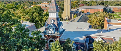 An outdoor aerial view of Ambrose Hall during the summertime, surrounded by green trees.